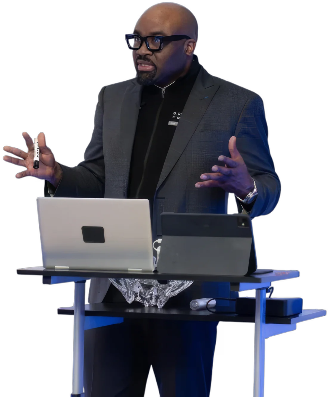 Babajide Ogunseinde speaking at a lectern with a laptop and tablet