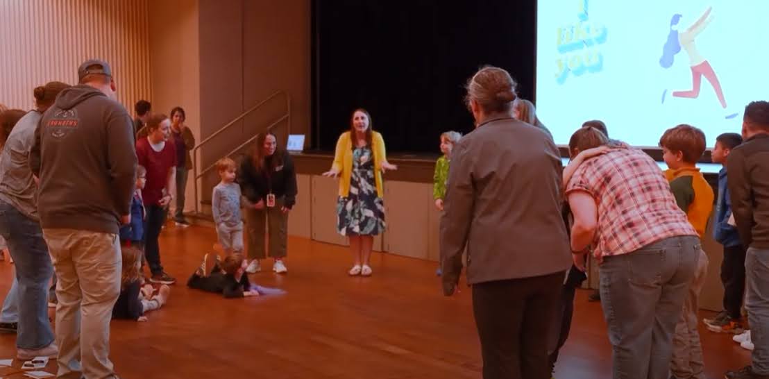 Erica Buchholz leading a Becoming Playful Playshop with parents and children in a hall