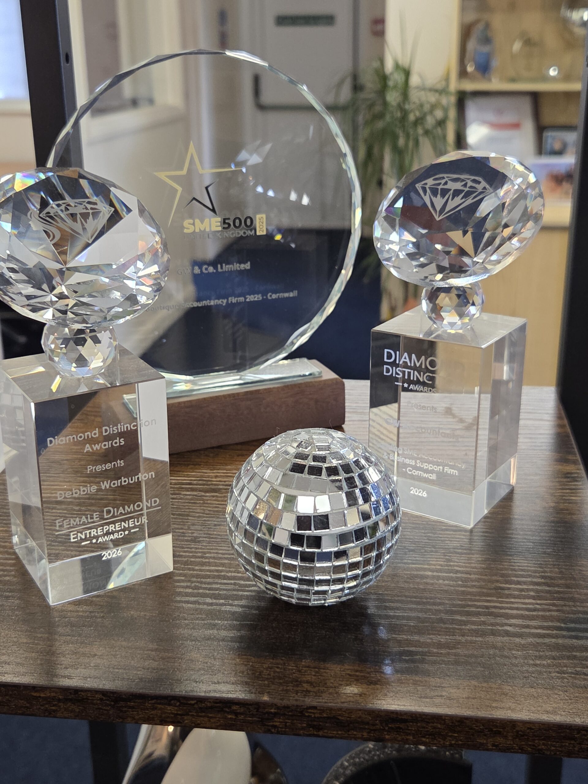 Debbie Warburton's awards on a desk at GW & Co, including the Female Diamond Entrepreneur Award 2026 and an SME500 UK 2025 plaque
