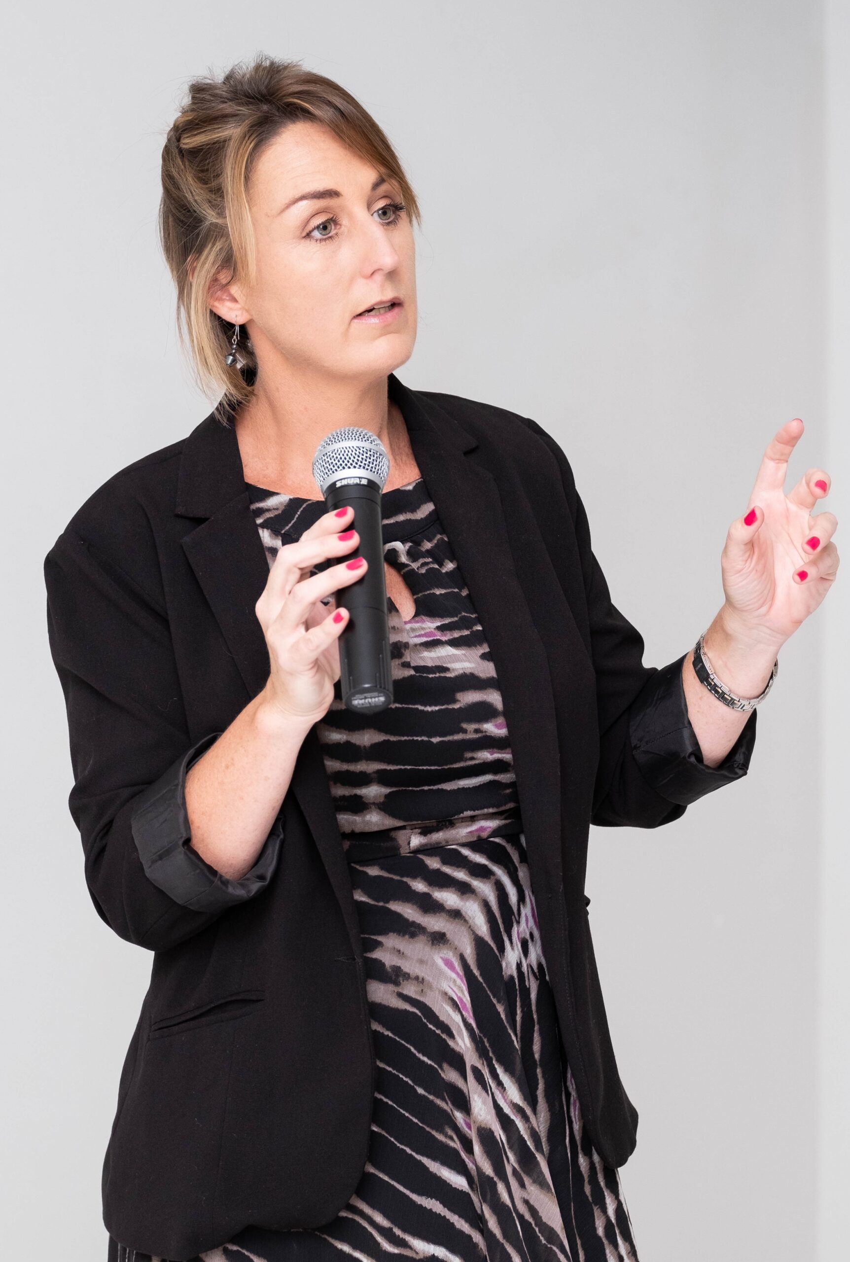 Bronwyn Crawford speaking into a microphone and gesturing as she explains a point