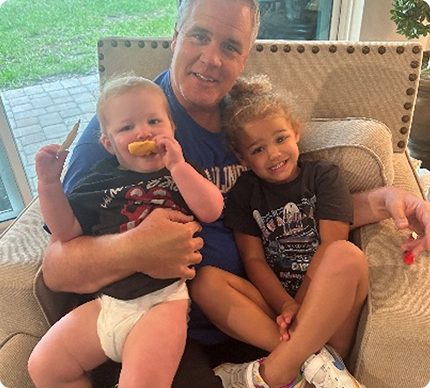 Darryl Heffline on a sofa with his two grandchildren