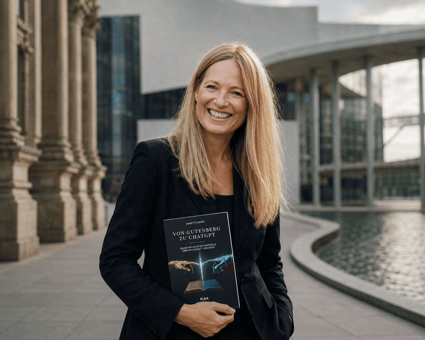 Dr. Annette Doms smiling and holding her book Von Gutenberg zu ChatGPT outdoors in front of a modern building