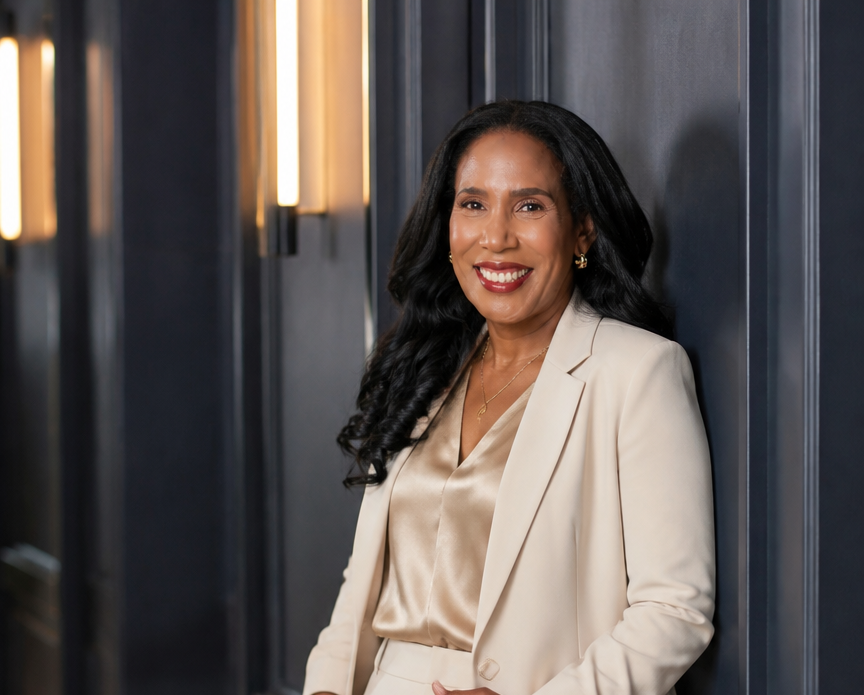 Eva Aimable-Kolosko in a beige suit leaning against a dark navy wall