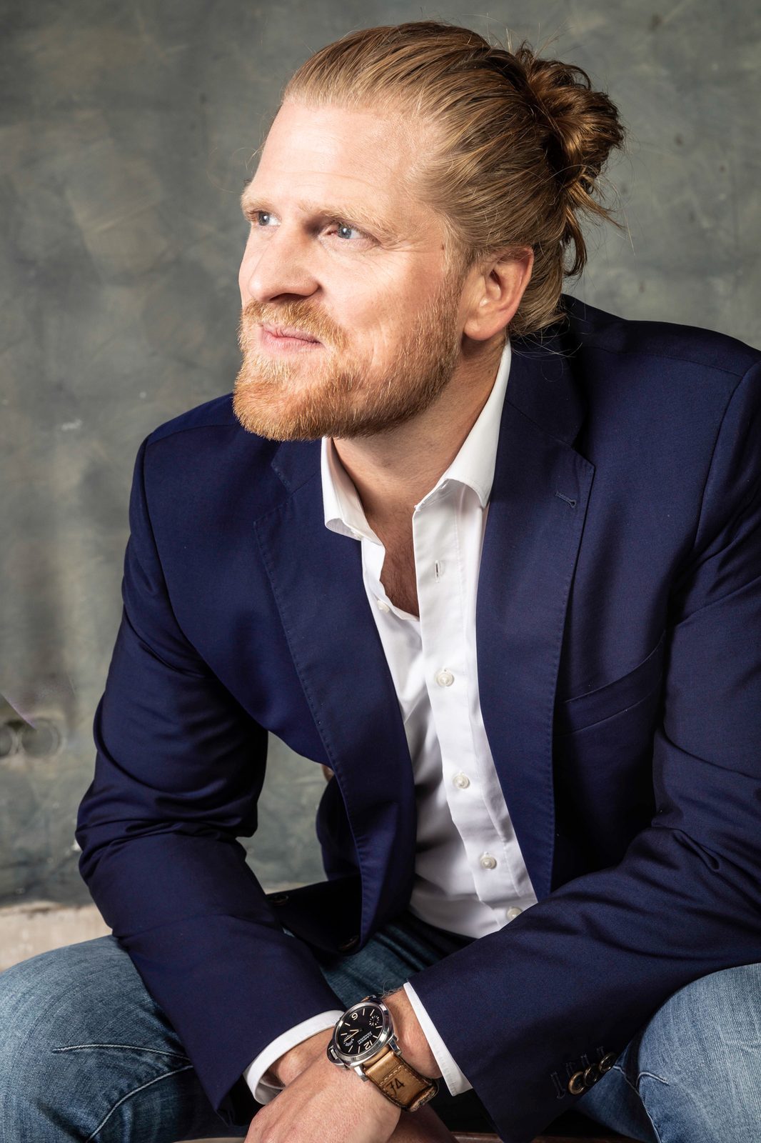 Frederic Lanz seated in a navy blazer and white shirt, looking to one side