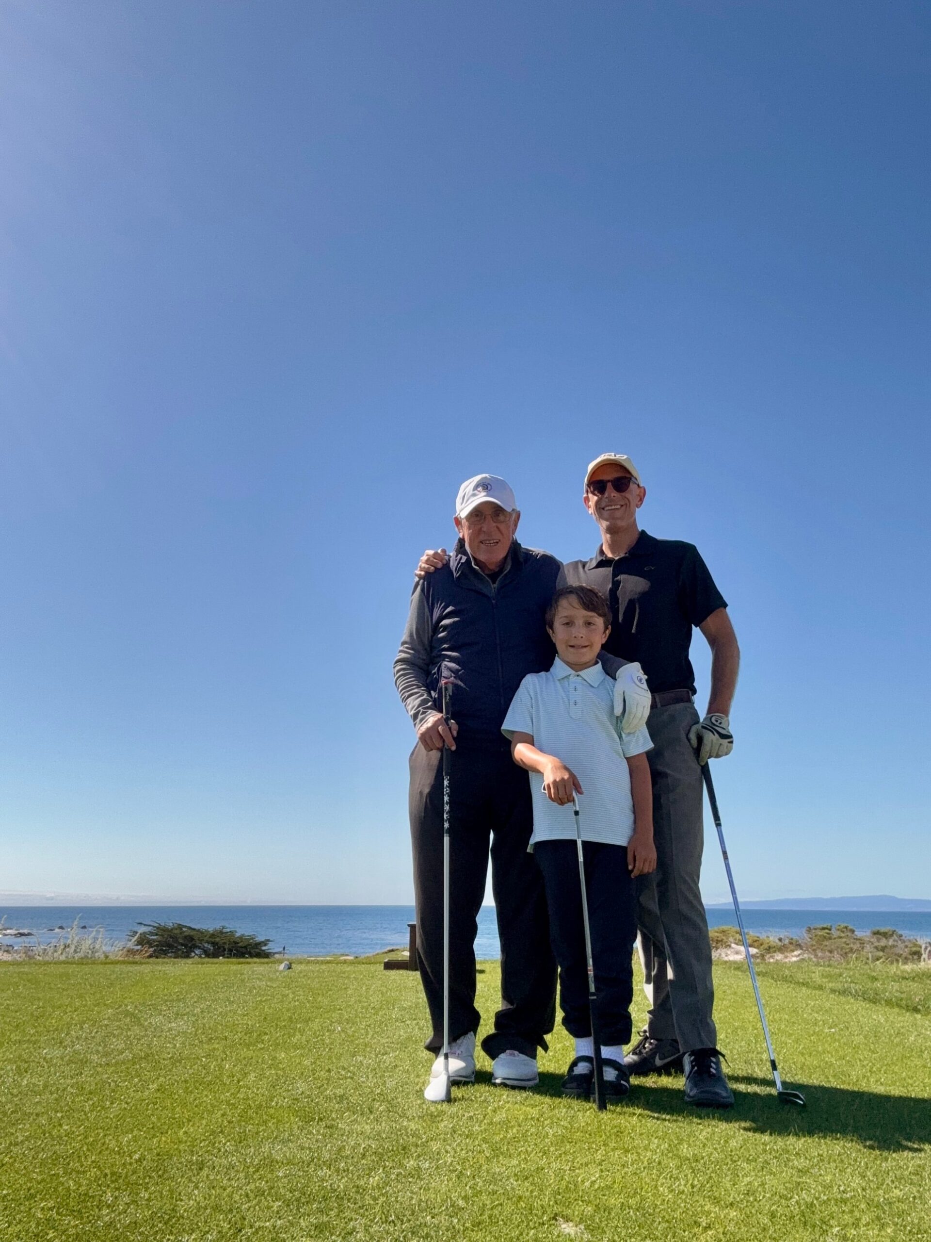 Joseph R. Bronson on a golf tee above the ocean, standing with two other golfers