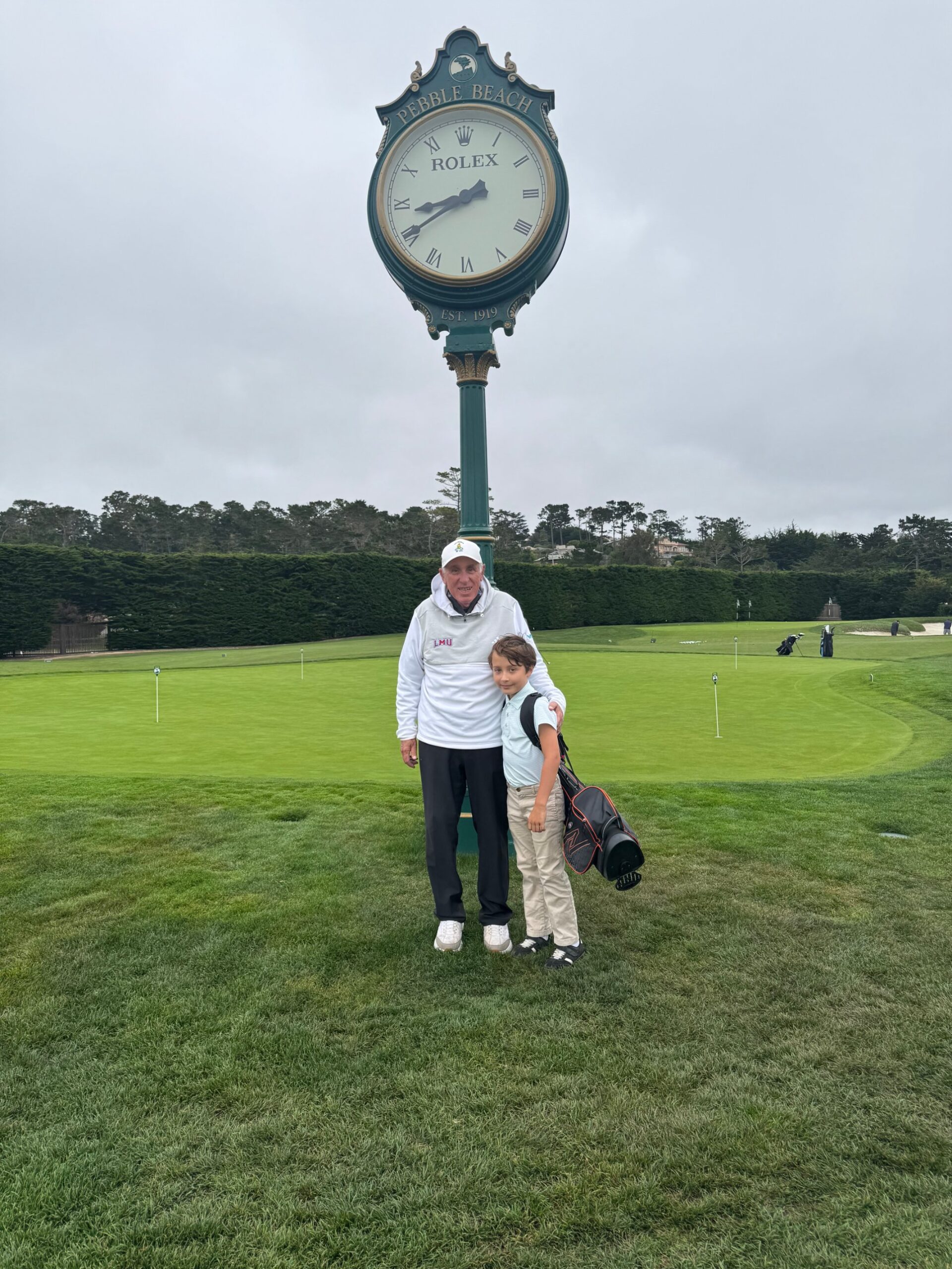 Joseph R. Bronson with a young golfer beneath the Rolex clock at Pebble Beach