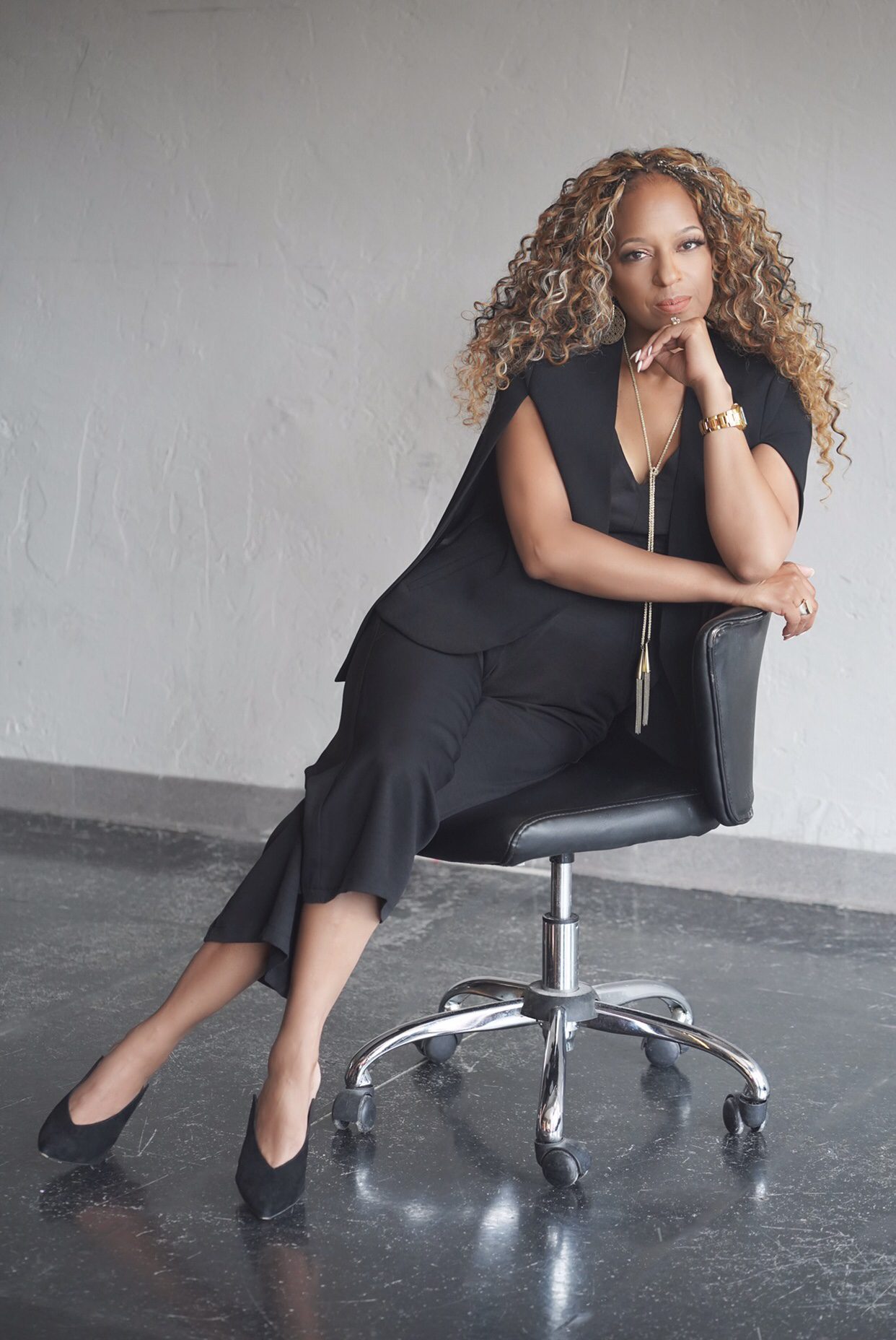 Michelle Patterson Wimes seated on a studio chair in a black outfit