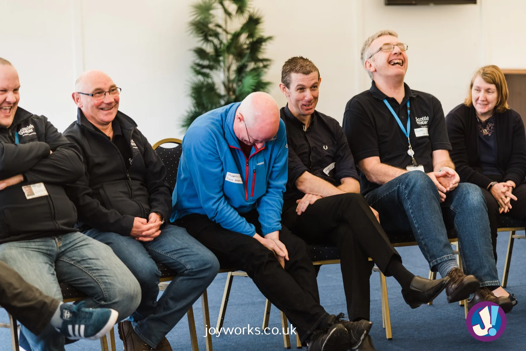 A Scottish Water team laughing on chairs in a circle at a Joyworks session
